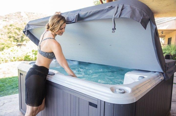 homeowner opening a sundance spas hot tub cover