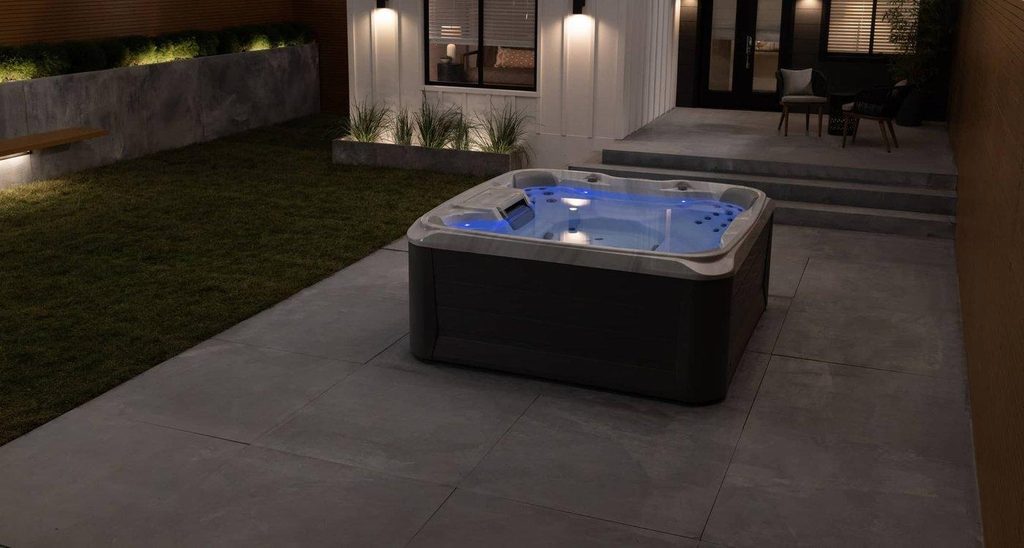 sundance spas 680 series edison hot tub on a patio in the evening